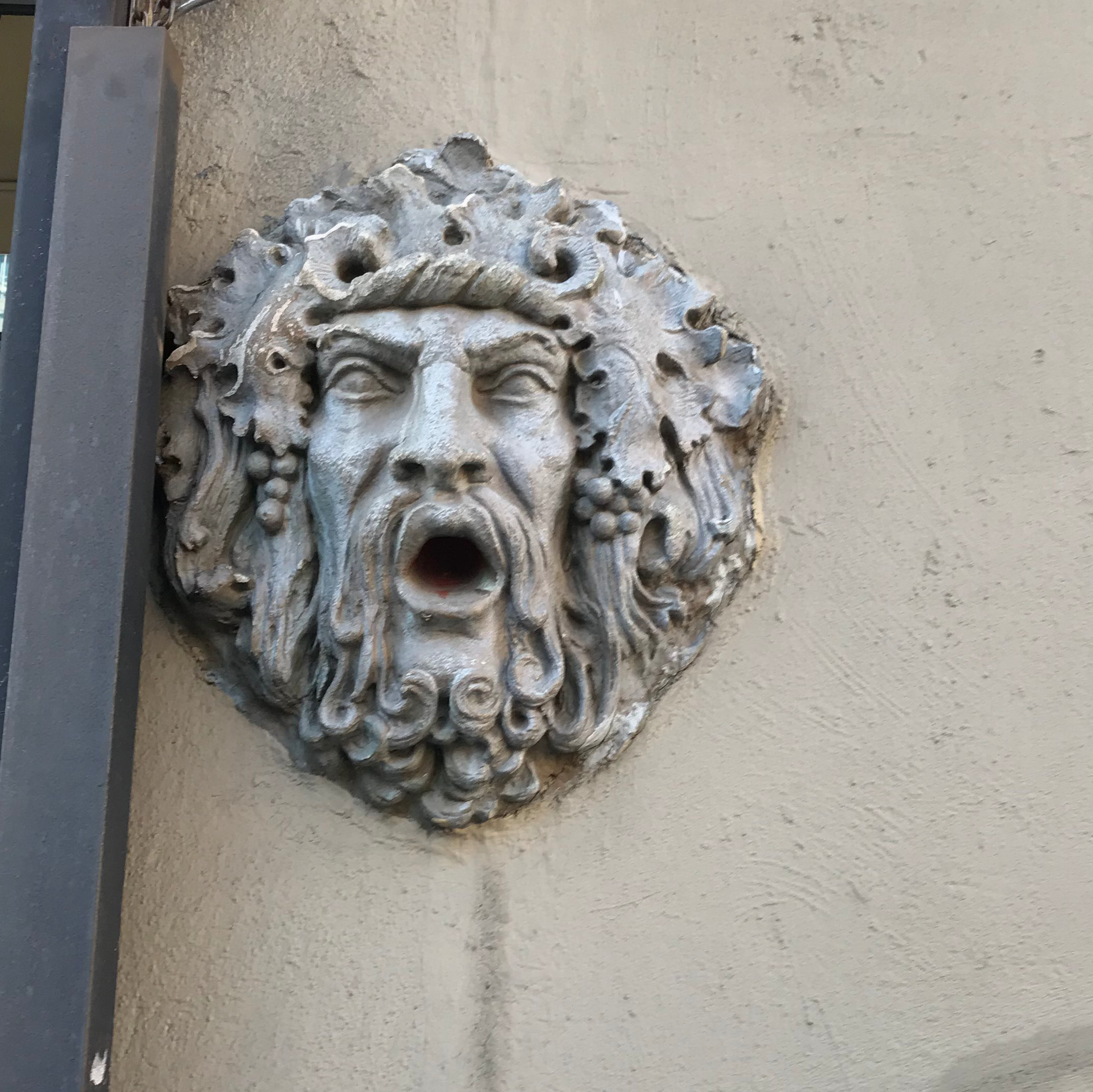 a statue of an angry looking man with a beard and his mouth open on the side of a building
