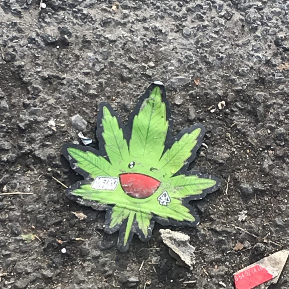 a cut out of weed sticker with the face of a takashi murakami flower on the ground